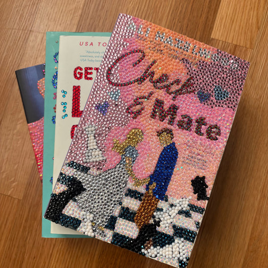 Decorative book with 'Check & Mate' text and embellishments on a wooden surface