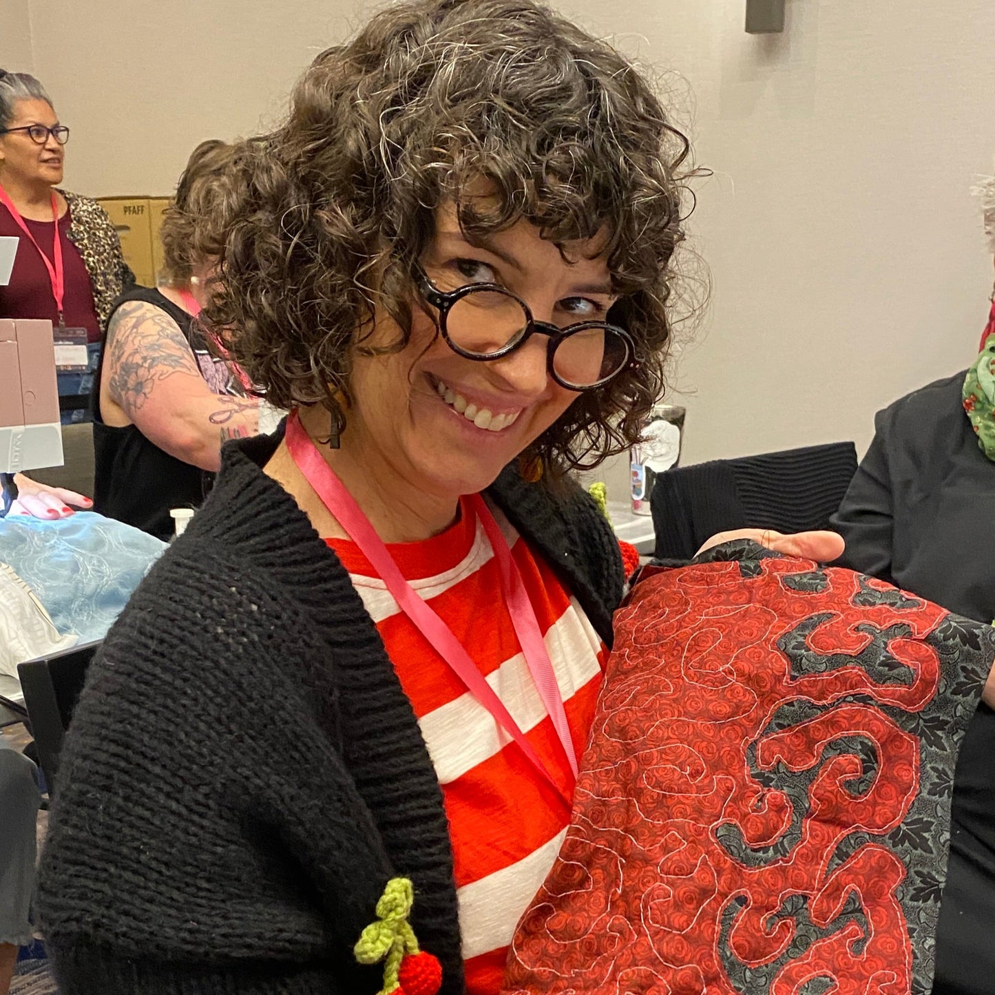 A person is smiling and holding up a red and black negative reverse applique bandana.