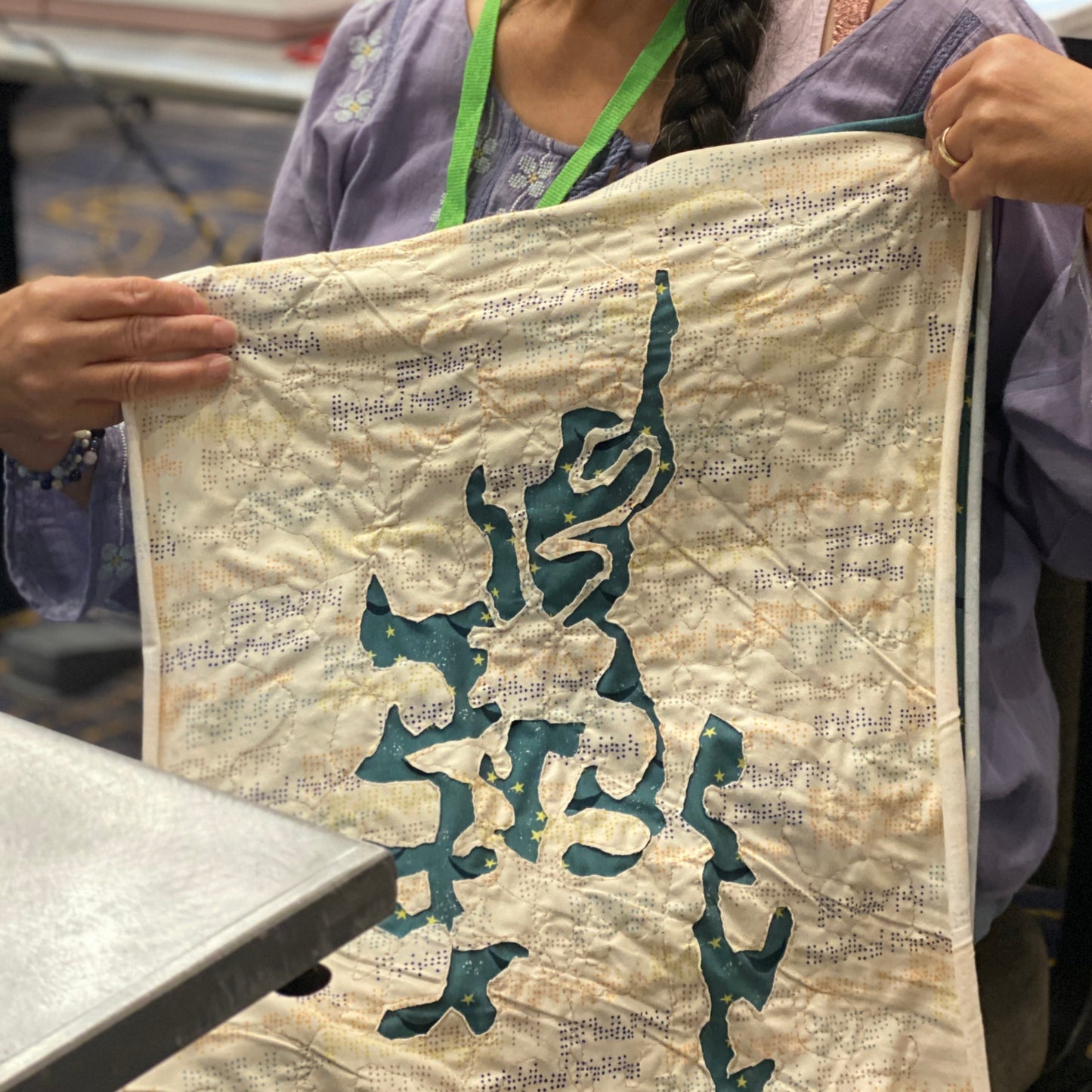 A person is holding up their in progress applique bandana.