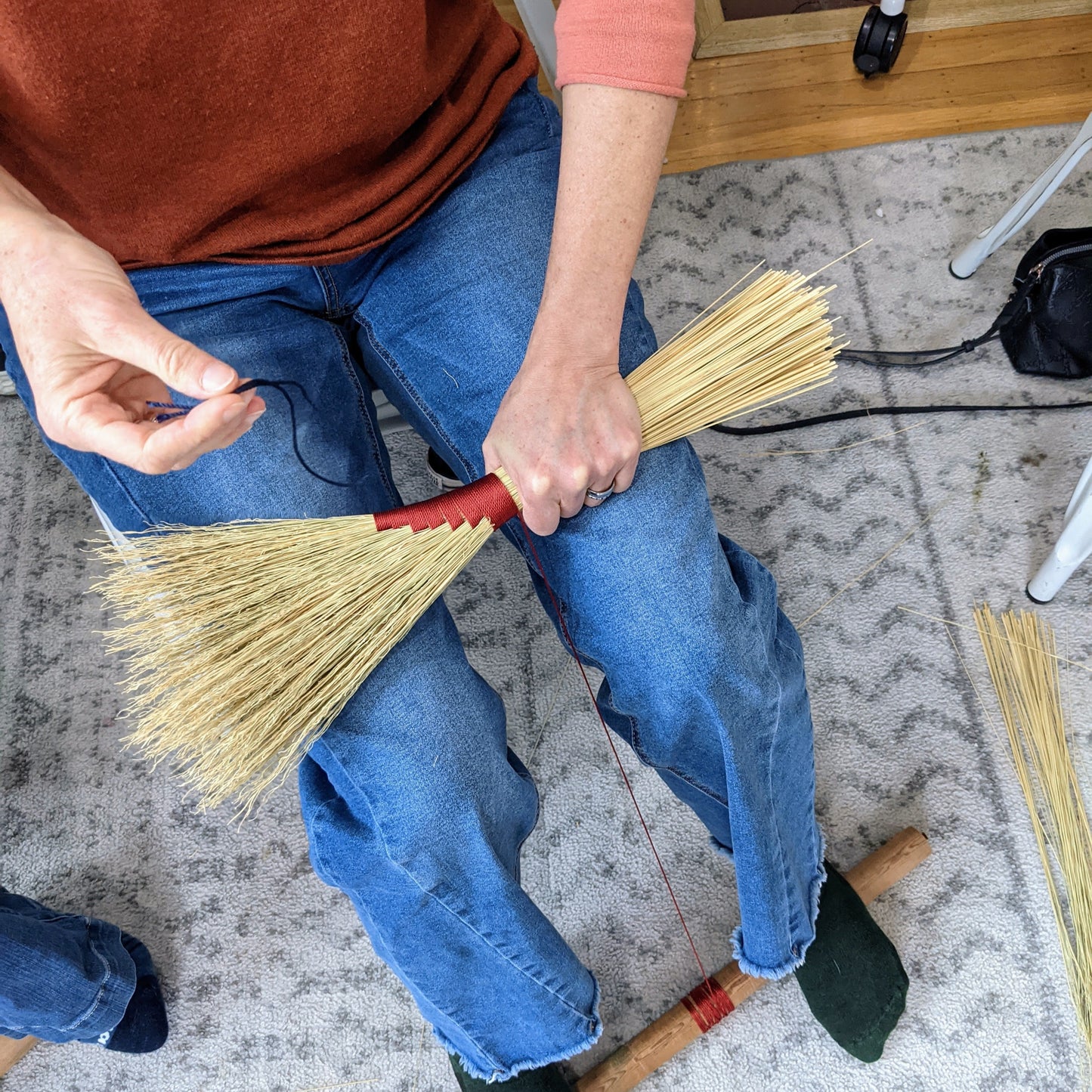 In progress photo of a person working on creating their hand broom. It is shot from above.