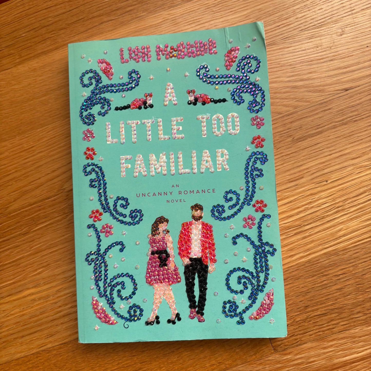 Book titled 'A Little Too Familiar' with decorative cover on a wooden surface