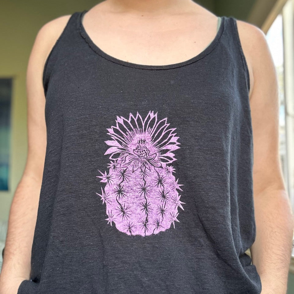 A person is wearing a tank top with a pink cactus block printed in the center.