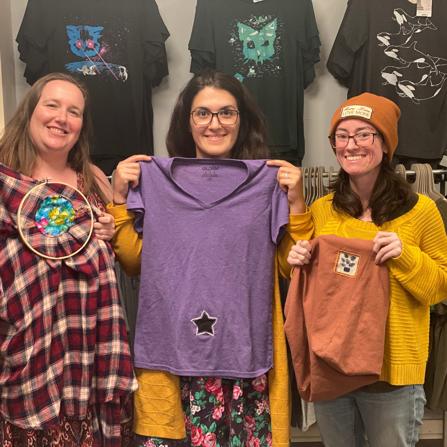 Three people holding up their reverse applique hand sewing projects that they made in class at Monster.