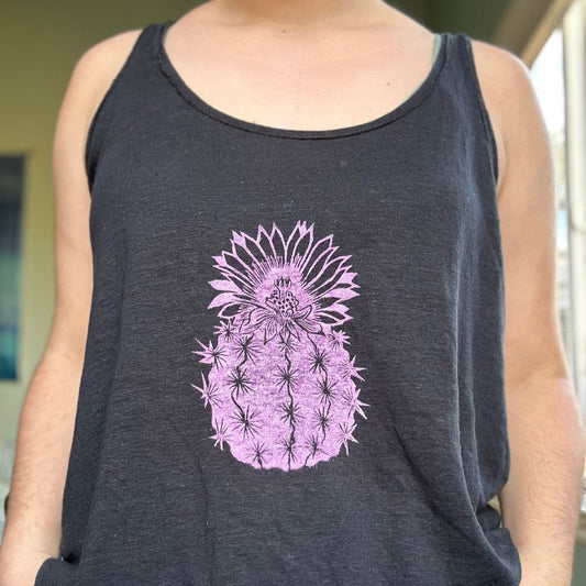 A person is wearing a tank top with a pink cactus block printed in the center. 