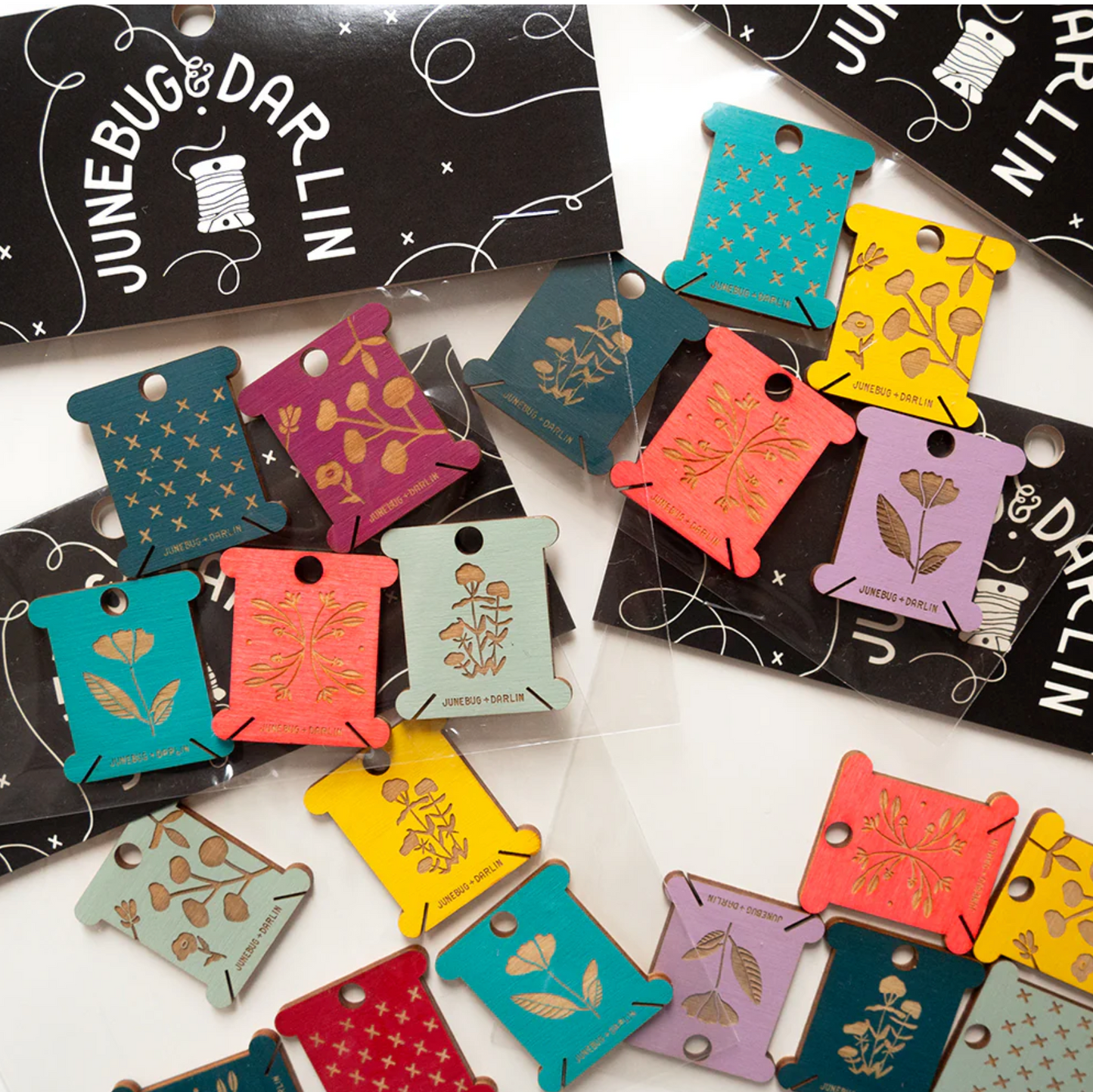 Packaged examples of floss holders from Junebug and Darlin'. Each pack is a random assortment of floss bobbin colors and designs. 