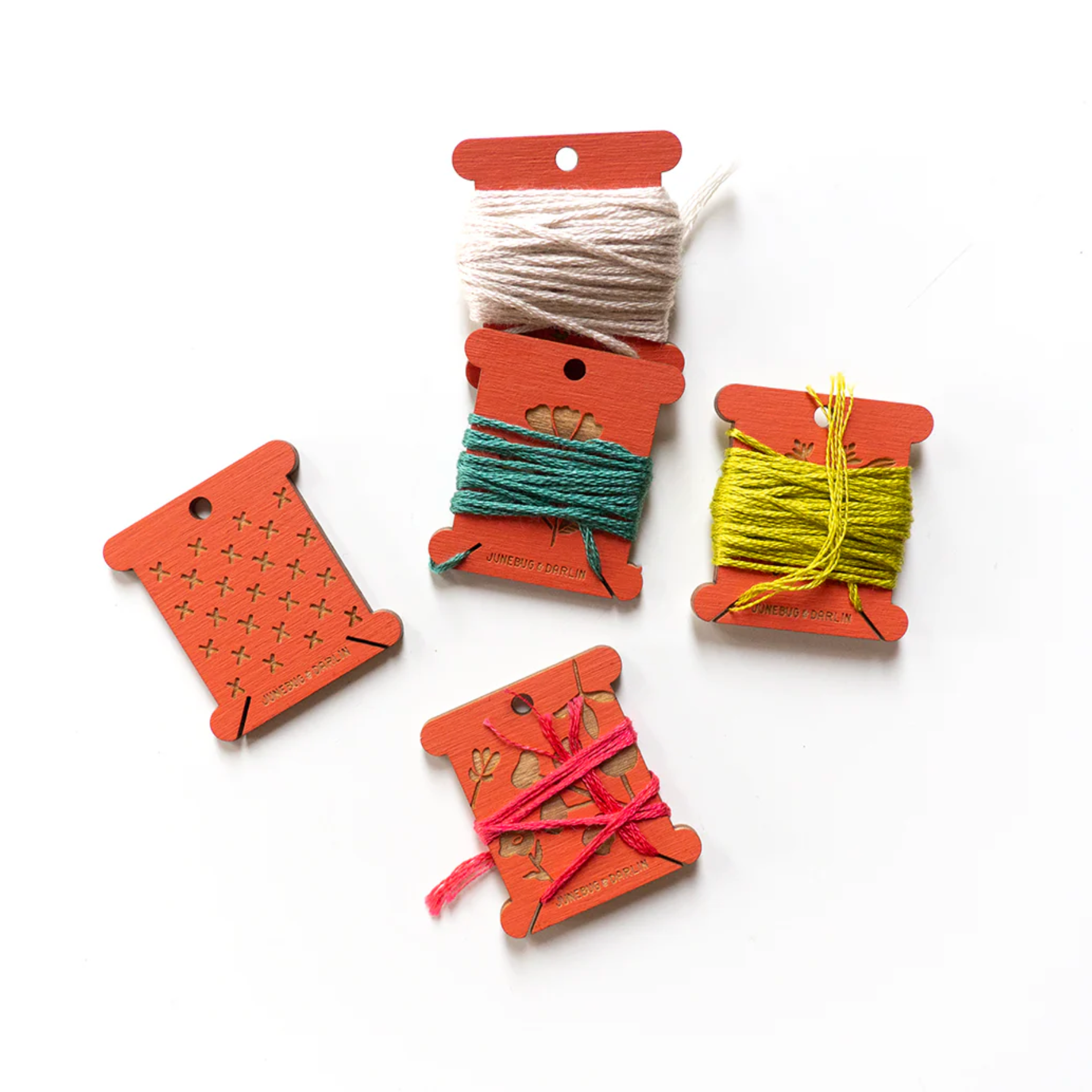 A photo of coral floss bobbins in use. They have embroidery floss wrapped around them. 