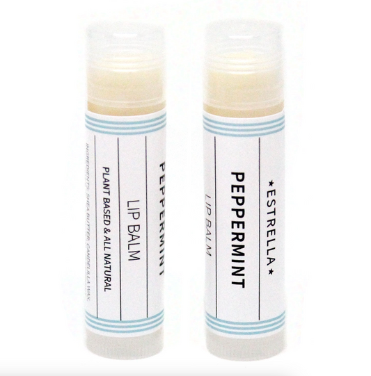 Two sticks of Estrella lip balm with peppermint flavor, set against a white background. The packaging is minimalistic with a predominantly white color and blue stripes.