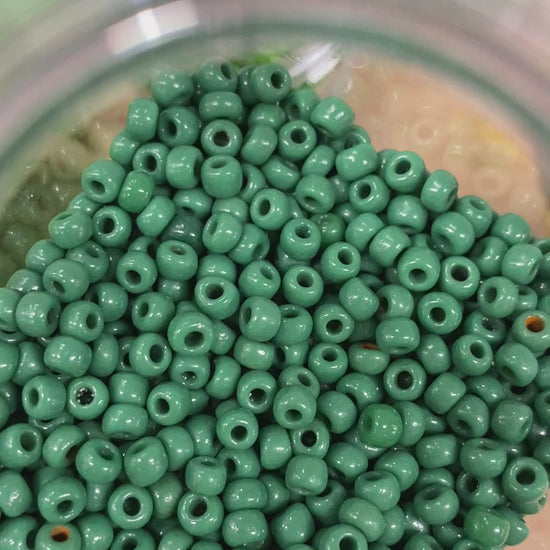 A short video of green beads being organized into a container.
