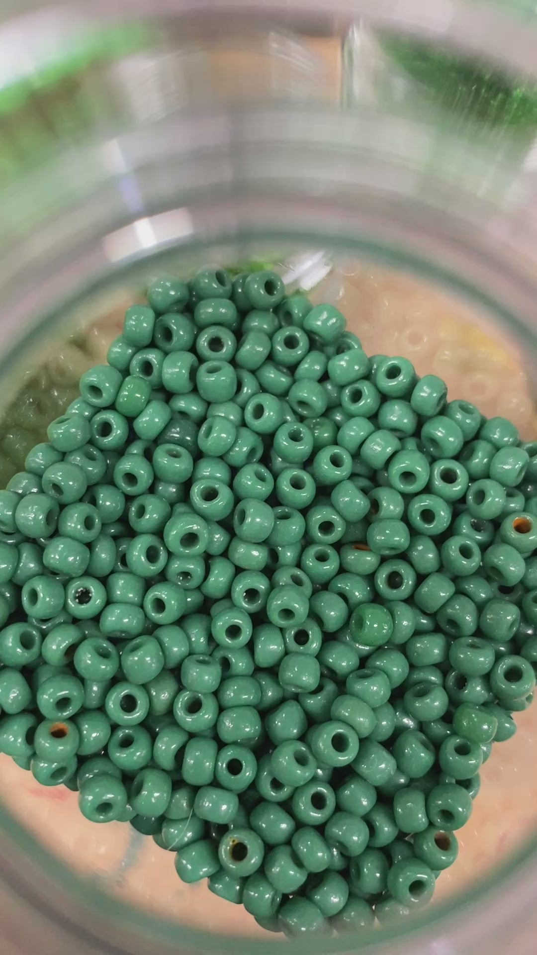 A short video of green beads being organized into a container.