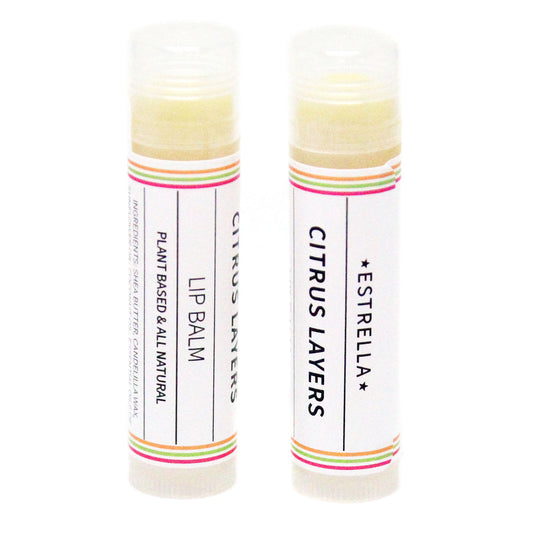 Two sticks of Estrella lip balm with citrus layers, one standing upright and the other lying down, both with colorful labels.
