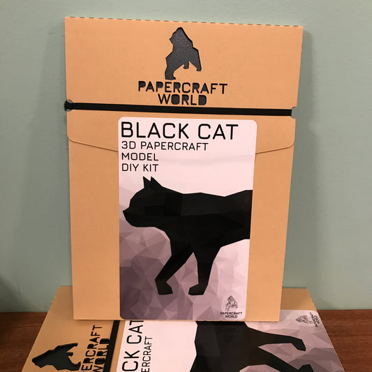 Packaging for Black Cat paper craft kit. It is kraft colored and has the papercraft world logo laser cut into the top of the package. It has an example of a completed black cat paper craft on the front. 